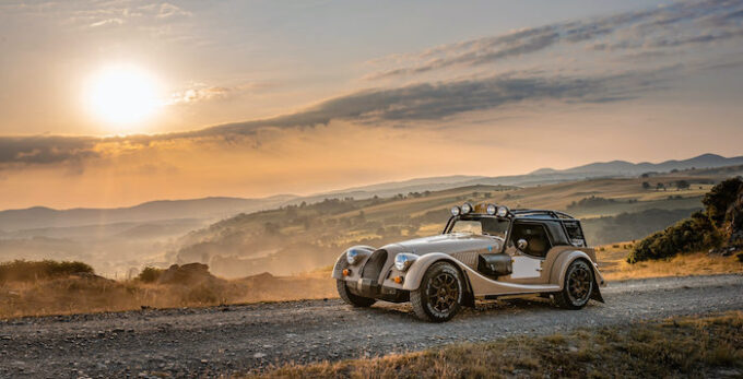 STATIC shot of Morgan CX-T on dirt road from side with sun in background