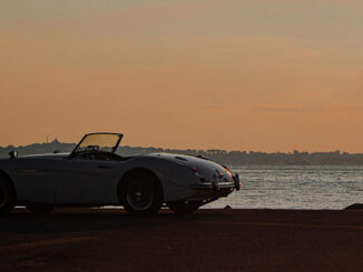 Austin-Healey roadster beside the water at sunset, from the Encounter 2026 organizer