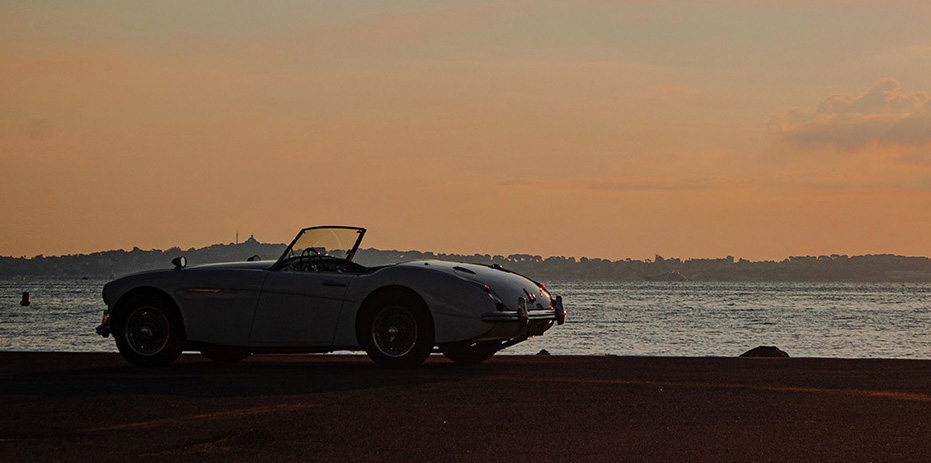 Austin-Healey roadster beside the water at sunset, from the Encounter 2026 organizer