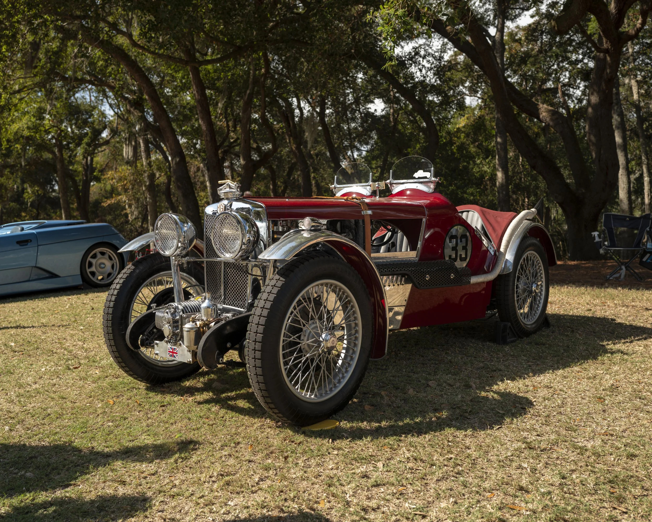 A vintage red 1930s MG race car with wire wheels and the number 33 on display under the live oaks at the Hilton Head Island Concours d'Elegance