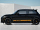 Side profile of the black MINI 1998 GT Edition with orange lower-body stripes and black JCW wheels.