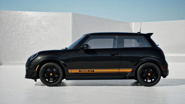 Side profile of the black MINI 1998 GT Edition with orange lower-body stripes and black JCW wheels.