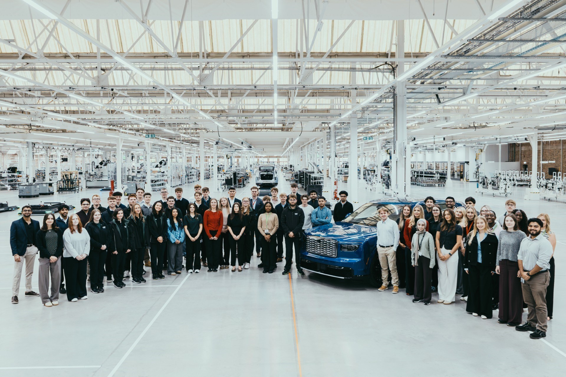 Bentley 2027 early careers cohort gathered around a blue Bentley inside the Crewe factory