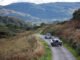 Two pre-war classic cars on a single-track road in the Scottish Highlands