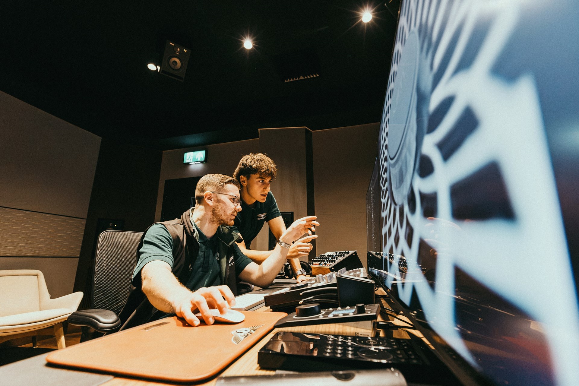 Two early careers colleagues reviewing designs on large screens in a Bentley studio