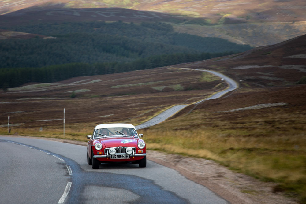 Red MGB roadster on a winding moorland road in the Highlands