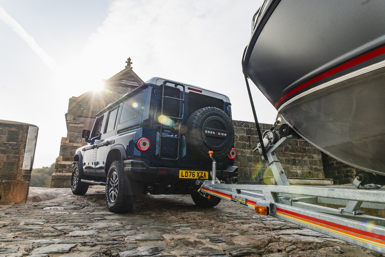 Rear view of the INEOS Grenadier Helmsman hitched to a boat trailer, showing rear access ladder and spare wheel