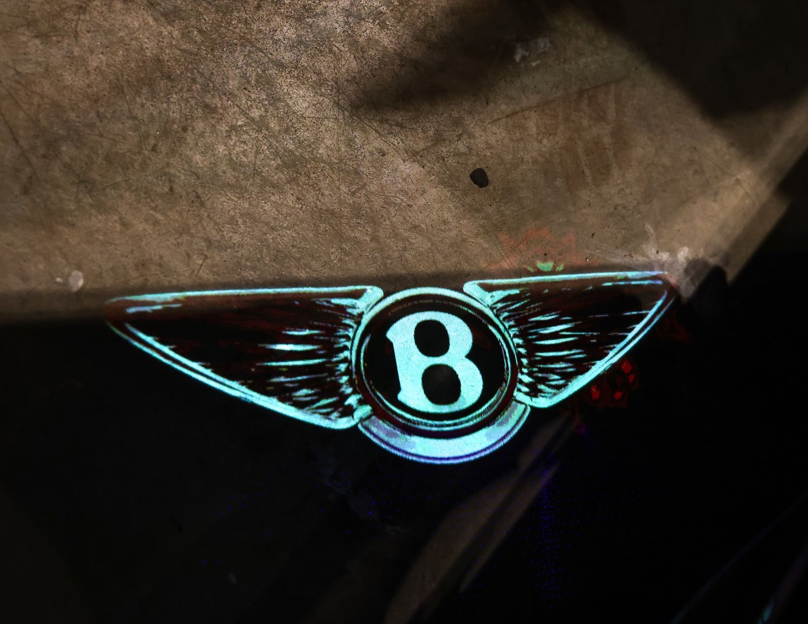 A glowing Bentley wings emblem projected at the CART Department gallery in New York