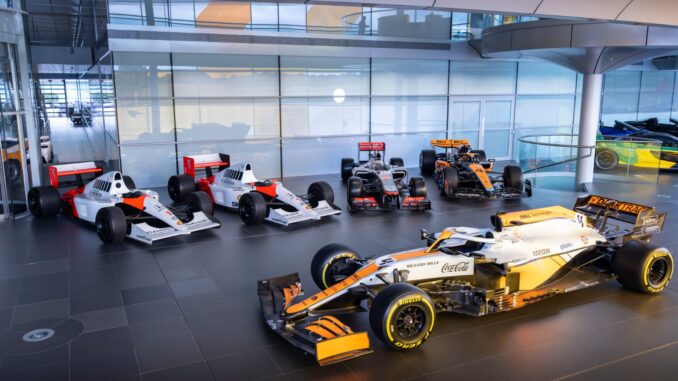 Five McLaren Formula 1 cars lined up inside the McLaren Technology Centre, led by the 2021 MCL35M