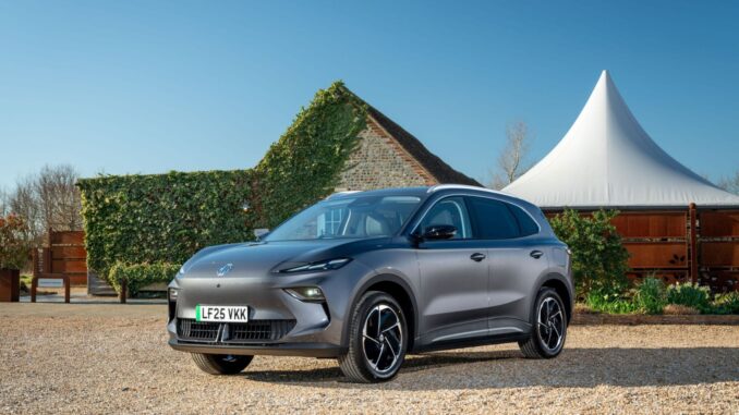 Grey MG MGS5 EV parked in front of flint barn and marquee, front three-quarter view