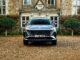 The MG MGS9 PHEV in Camden Grey parked on gravel in front of a stone country house, front view