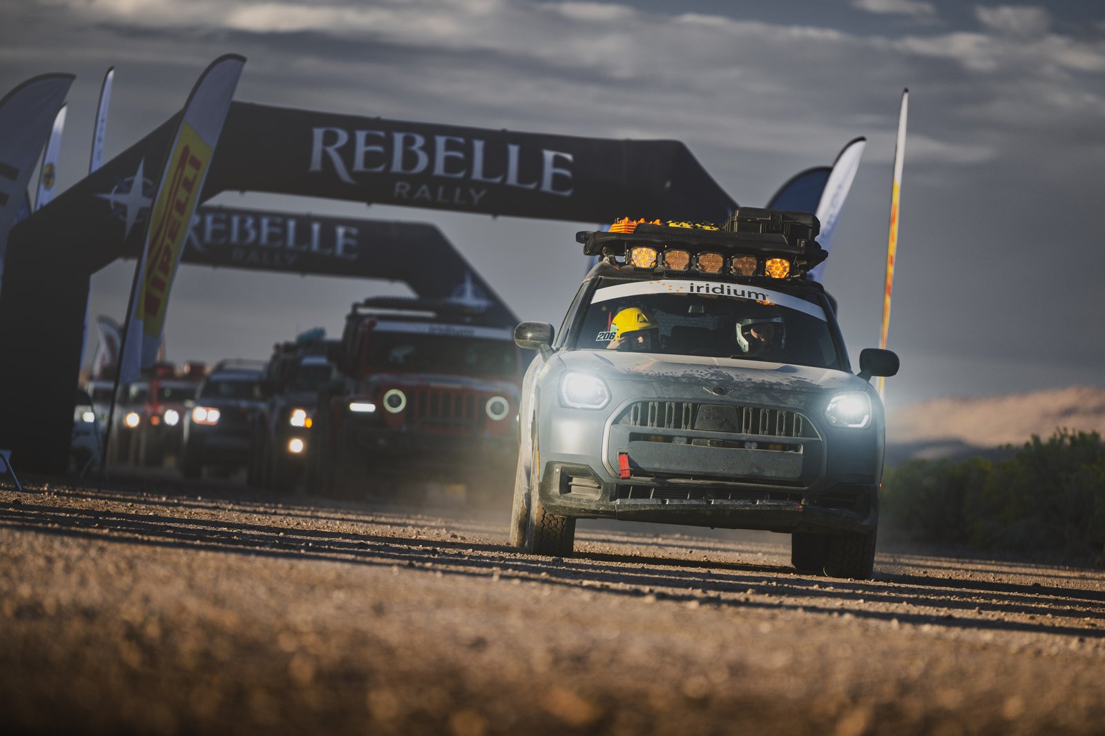 The MINI Countryman Untamed Edition leads the rally field away under the Rebelle Rally start arch, headlights on